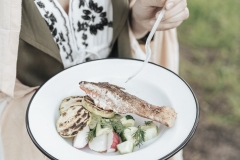 Crop woman trying salmon with vegetables